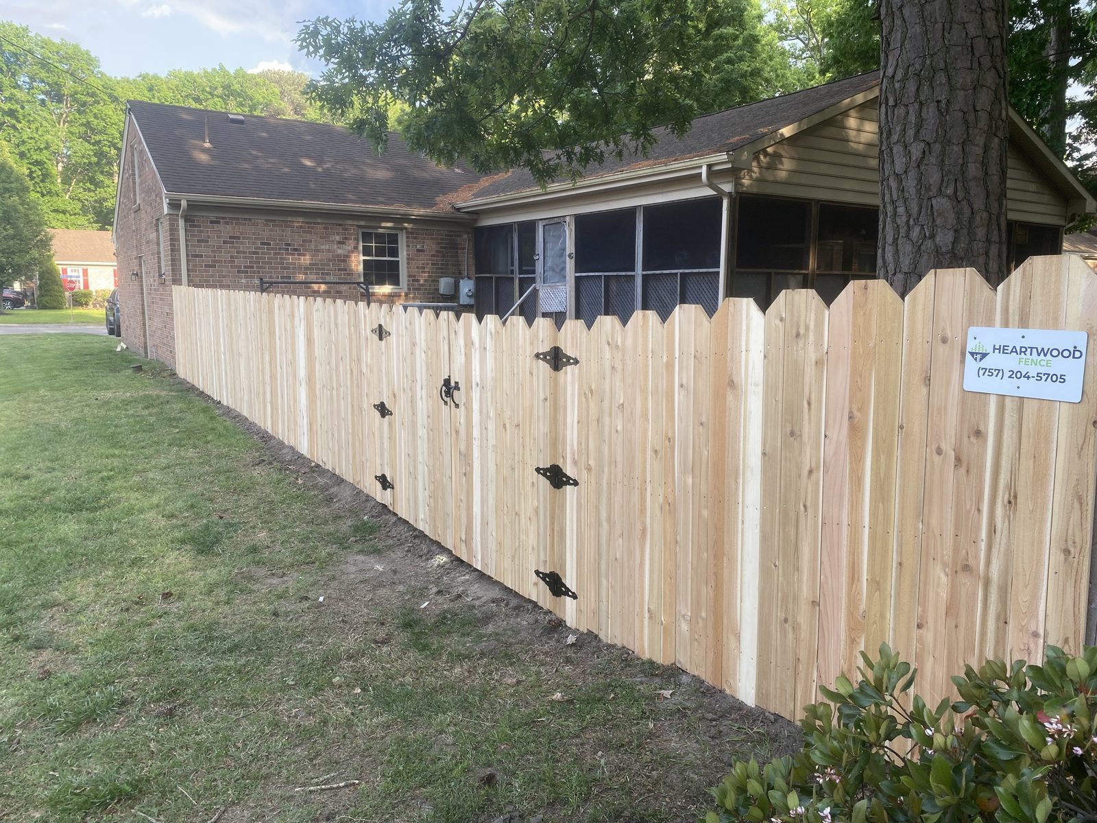 Cedar dog-ear picket fence with a Heartwood Fence sign