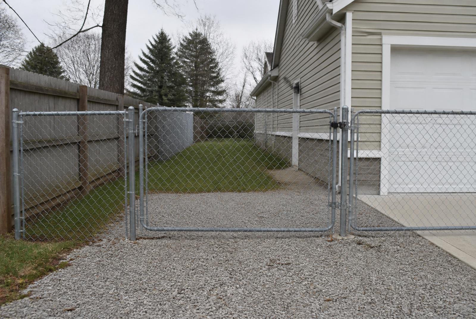 Galvanized chain link fence and swing gate along a driveway