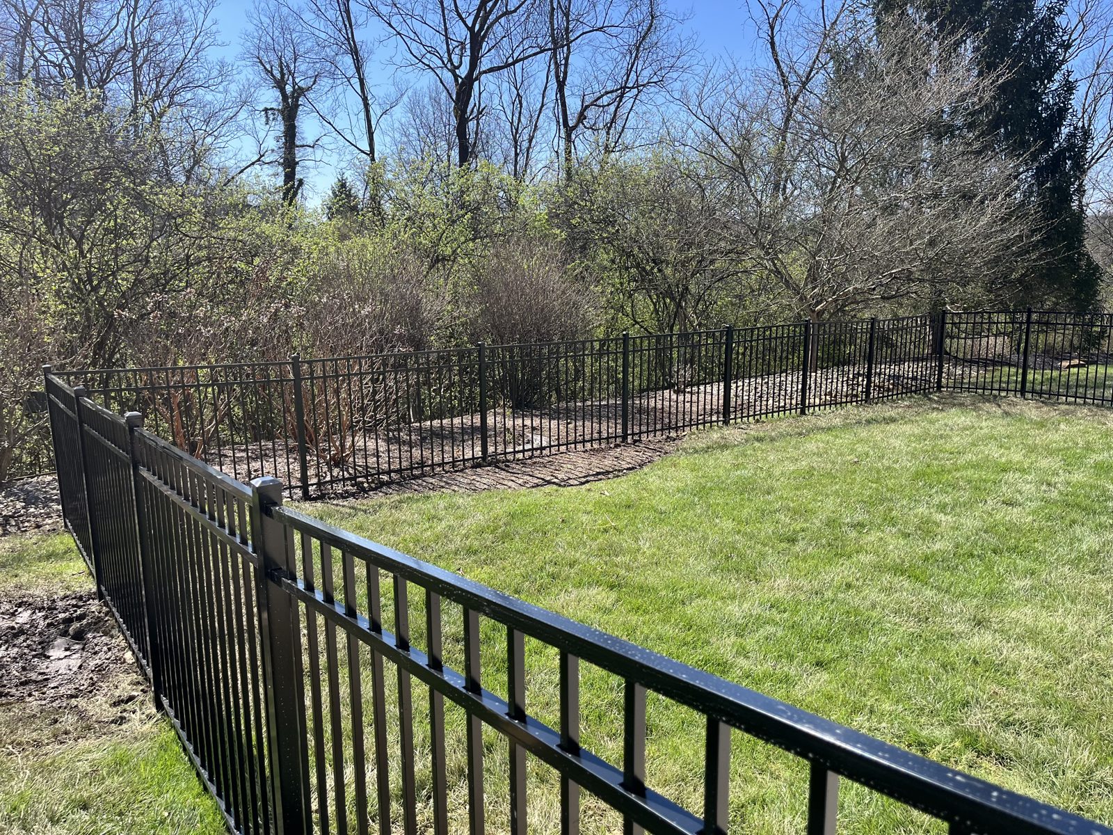 Black aluminum fence racked down a grassy slope