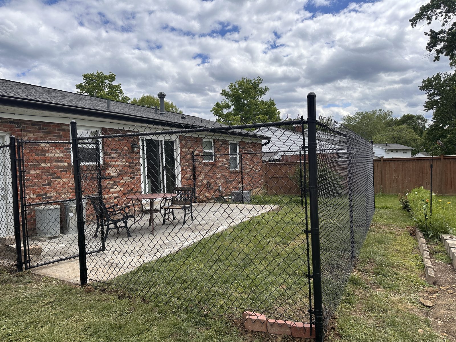 Black chain link fence behind a brick home