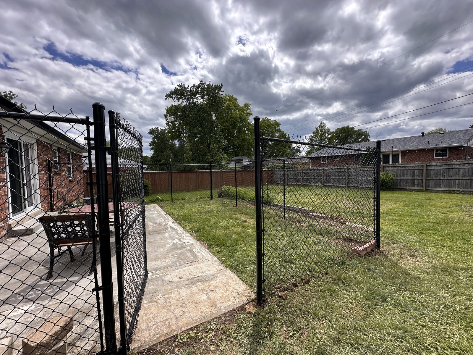 Black chain link fence enclosing a brick patio