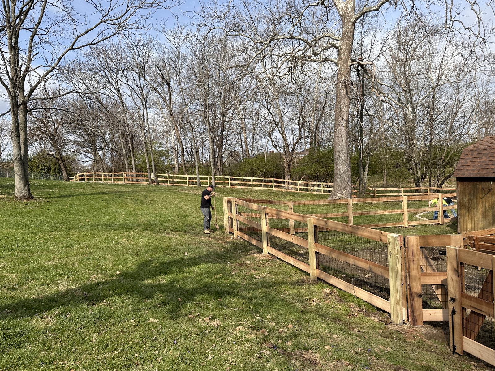 Heartwood crew installing a split rail fence with wire mesh
