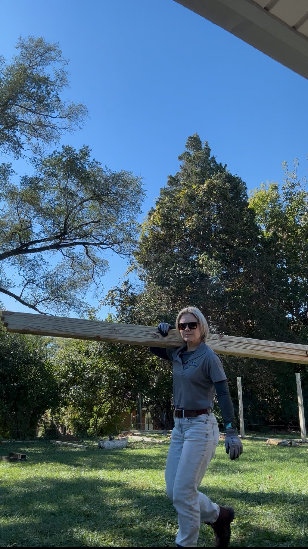 Heartwood crew member carrying a fence rail across a yard