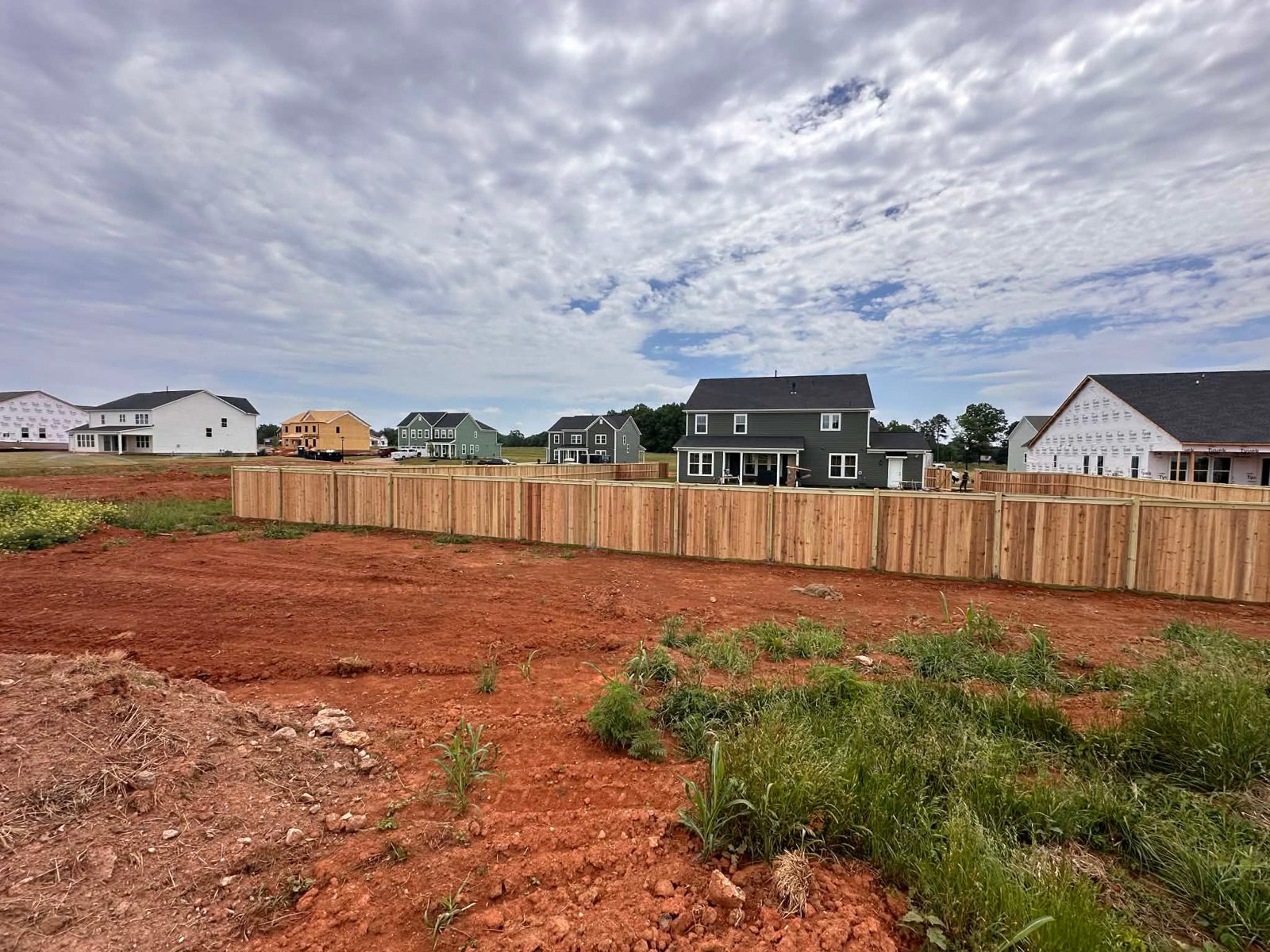 Long run of wood privacy fencing on a new-build lot in Greenville