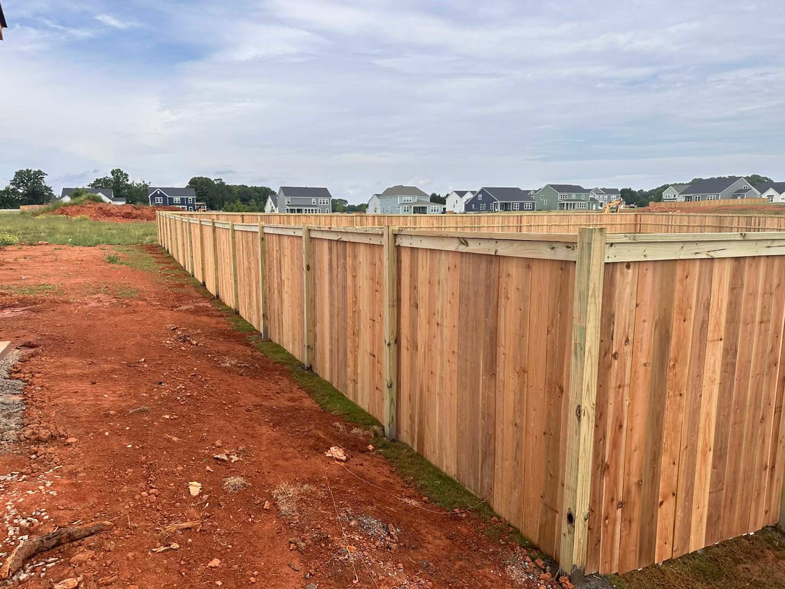 Wood privacy fence along a red-clay lot in Greenville