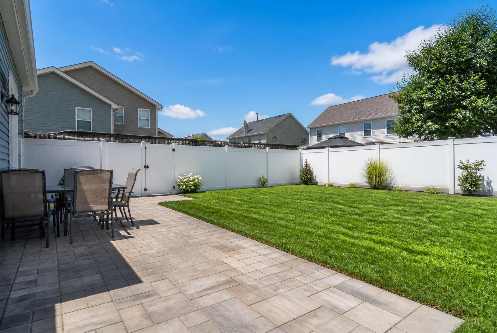 White vinyl privacy fence enclosing a backyard patio and lawn