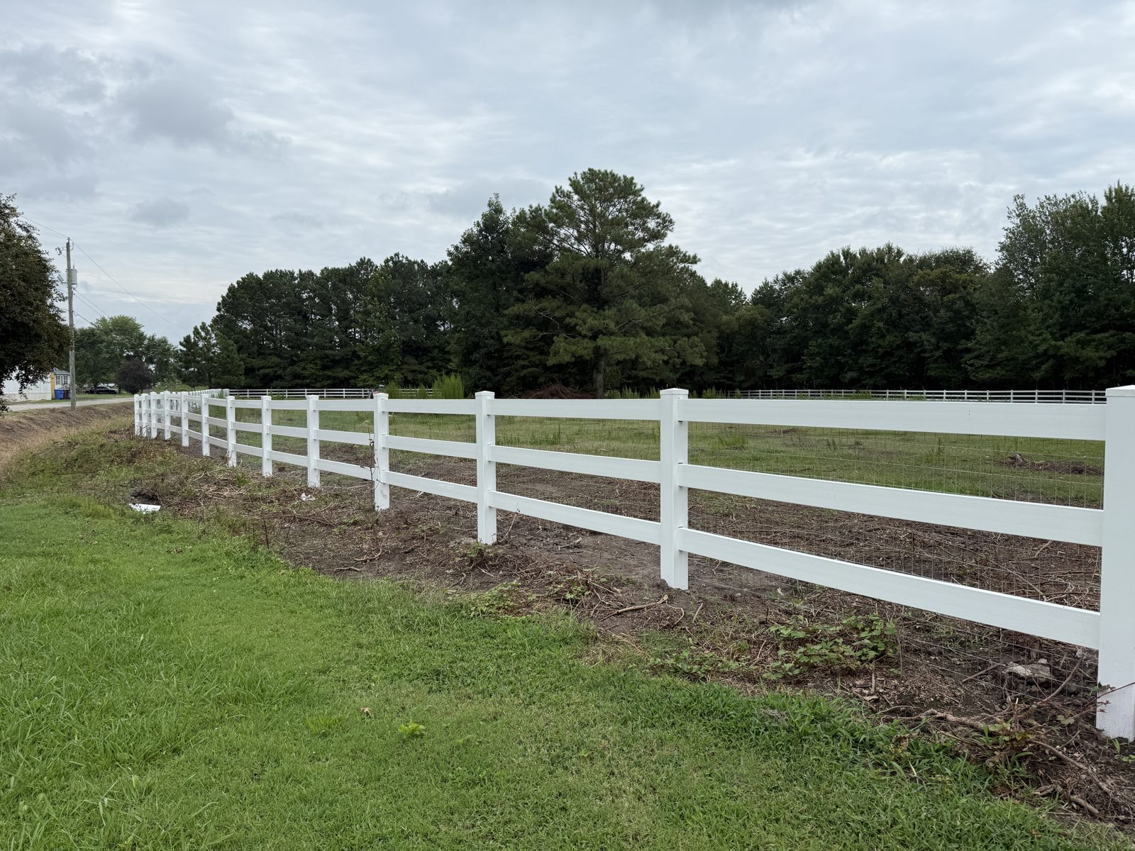 White vinyl ranch rail fence along a pasture